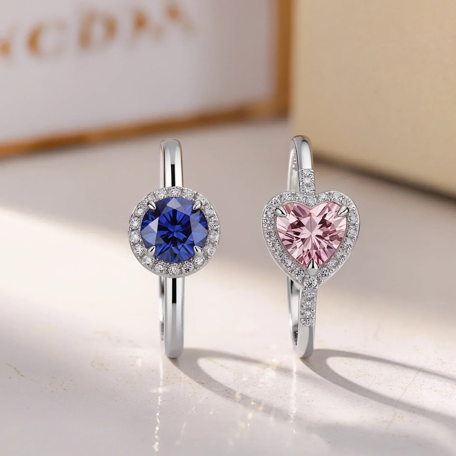 Two delicate gemstone rings in image_a0bb5d.jpg: a round blue sapphire halo ring and a heart-shaped pink morganite ring, illustrating romantic and durable alternatives for everyday wear.