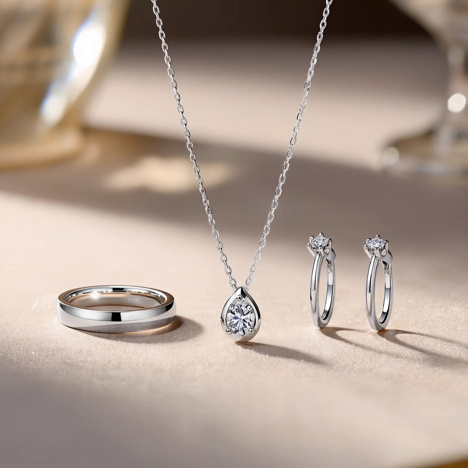 A fine jewelry collection featured in image_adeee6.jpg showcasing a sleek flat wedding band, a minimalist diamond pendant necklace, and two delicate solitaire rings to compare white gold and platinum colors.
